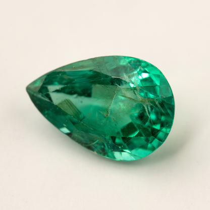 Pear emerald lying face-up on a pale surface from a lower angle.