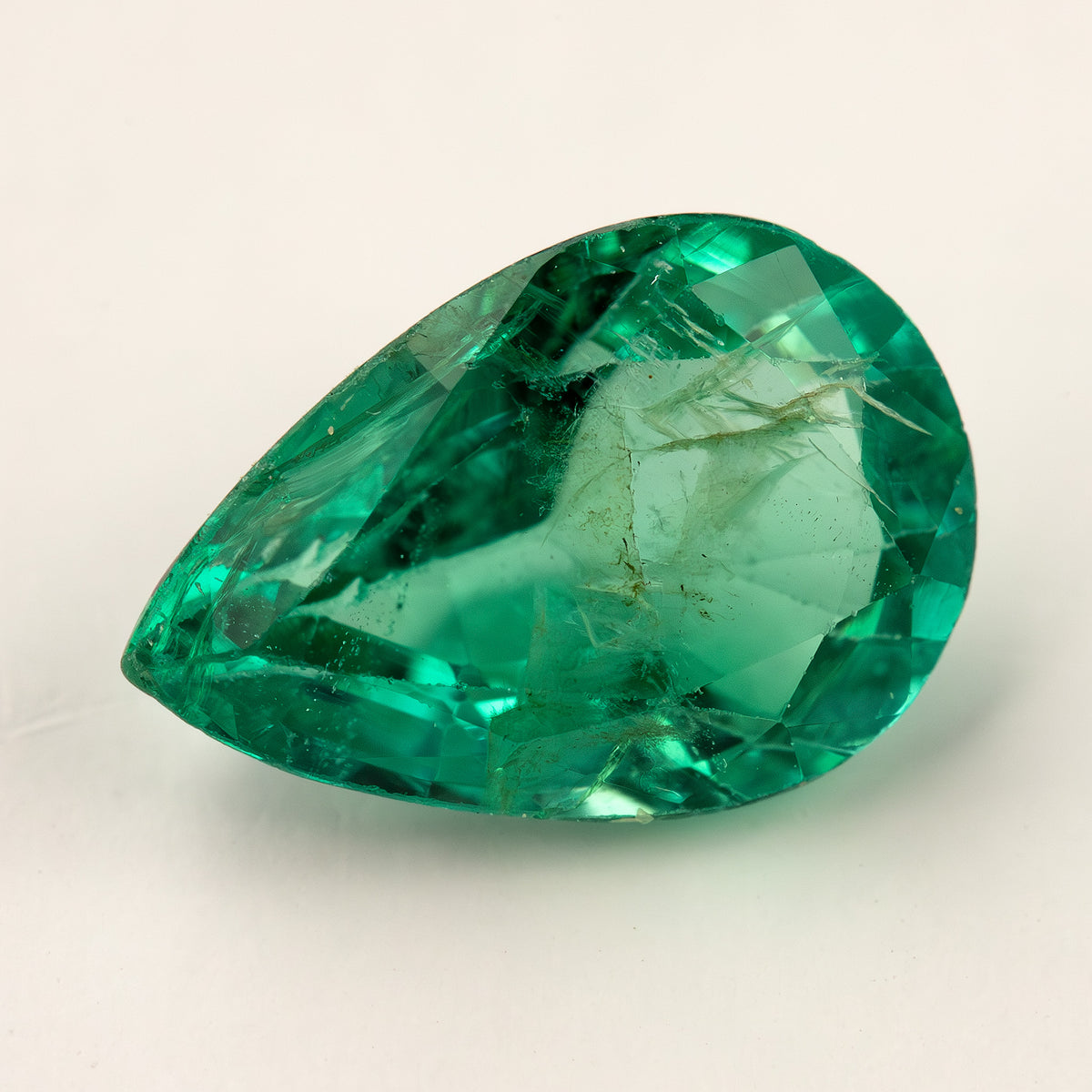 Tilted face-up view of the pear emerald showing facets and internal features.
