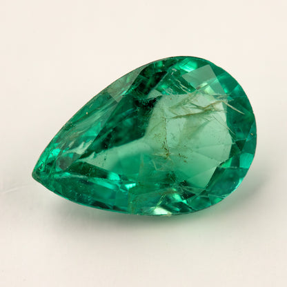 Tilted face-up view of the pear emerald showing facets and internal features.