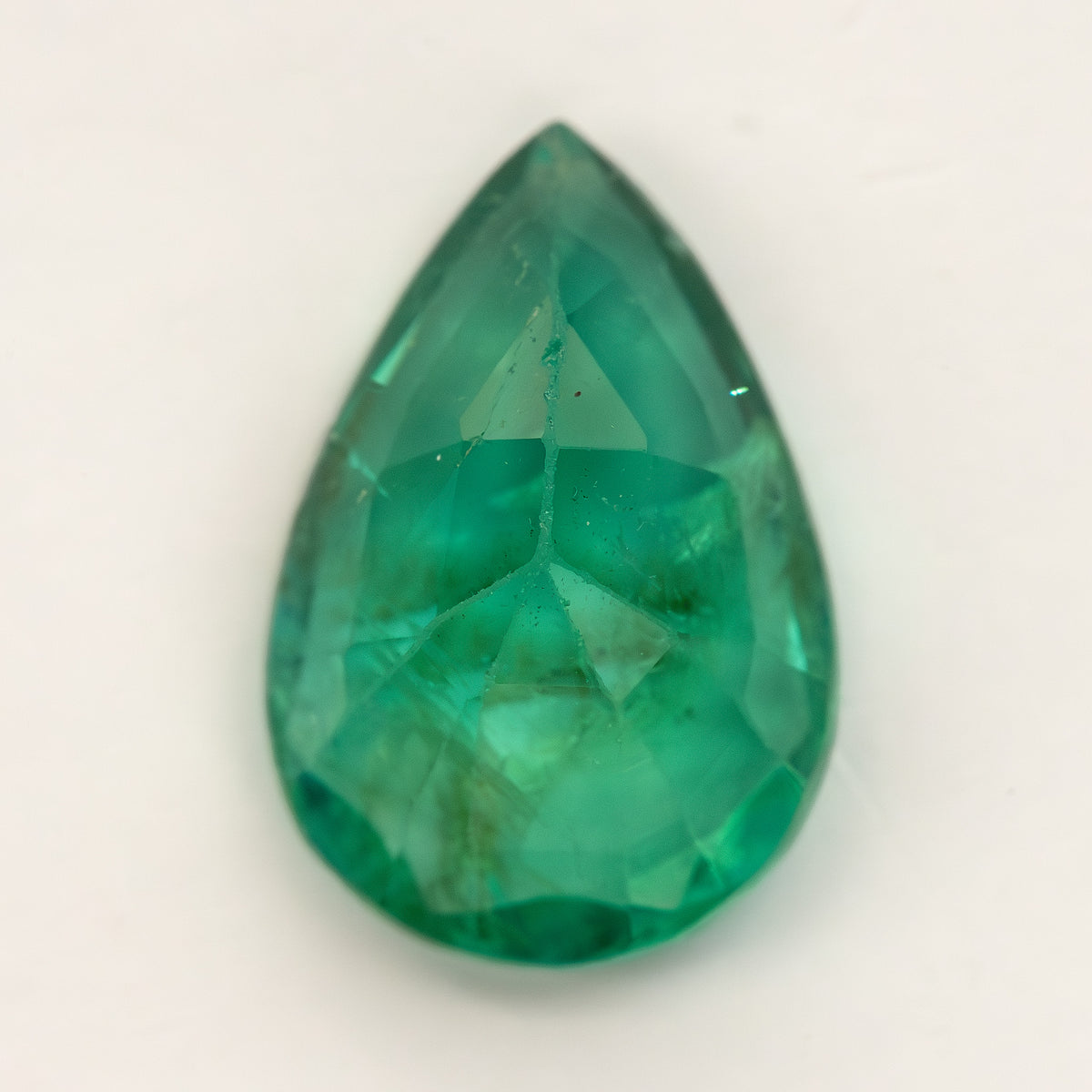 Reverse view of pear emerald on a pale surface showing pavilion facets.