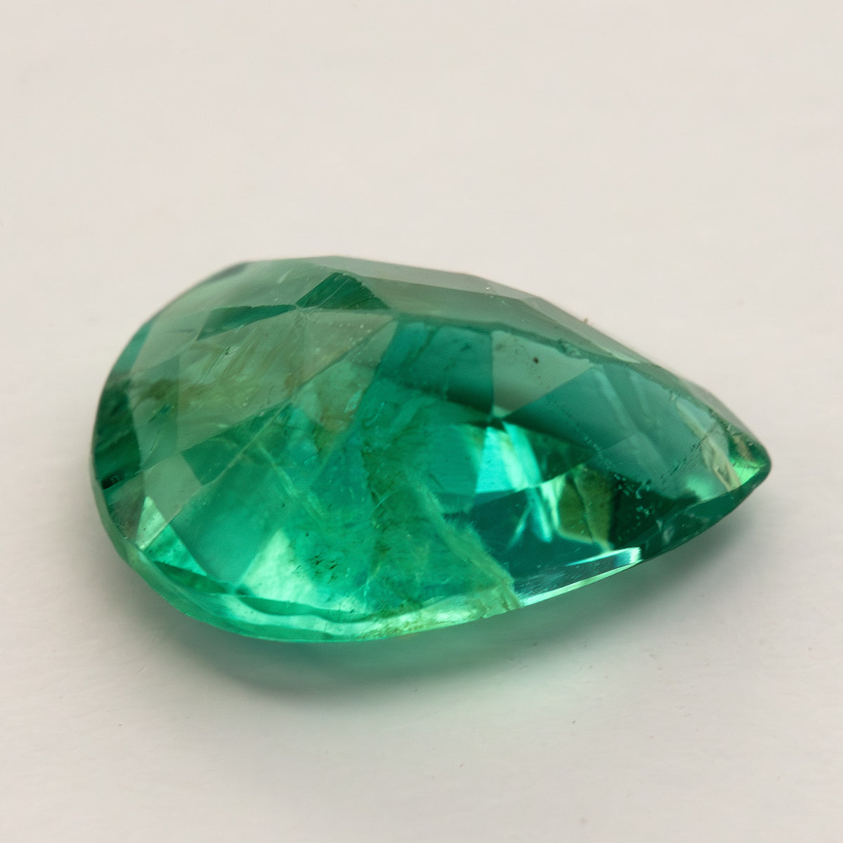 Low oblique view of pear emerald on a pale surface, showing depth and facets.