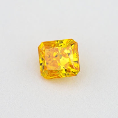 Angled crown view of the orange-yellow diamond, with bright reflections across its cut-cornered rectangular face.
