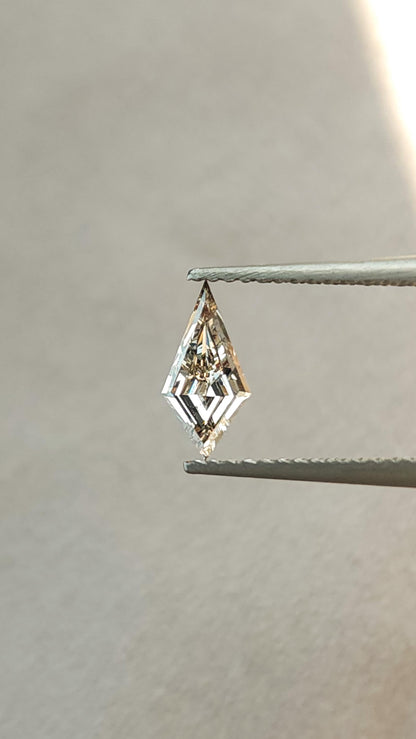 Face-up view of the exact light champagne elongated kite lab-grown diamond in tweezers, showing geometric step-cut reflections.