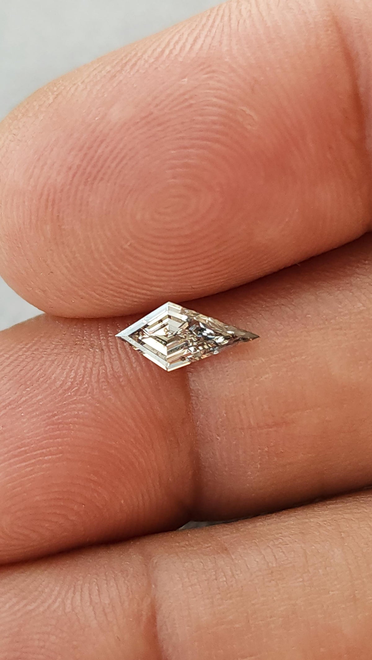 Second fingertip-scale view of the exact 0.39-carat elongated kite lab-grown diamond at a different reflective angle.