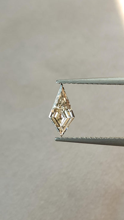 Alternate face-up view of the exact light champagne elongated kite step-cut diamond held upright in tweezers.