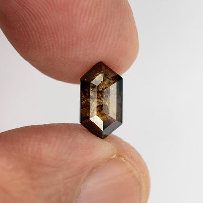 Dark brown Dutch marquise diamond held between fingertips, showing its elongated proportions and pointed outline.