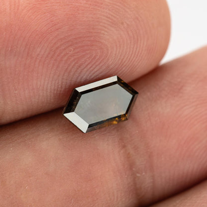 Opposite face of the diamond resting on a fingertip, showing contrasting facet reflections and visible natural inclusions.