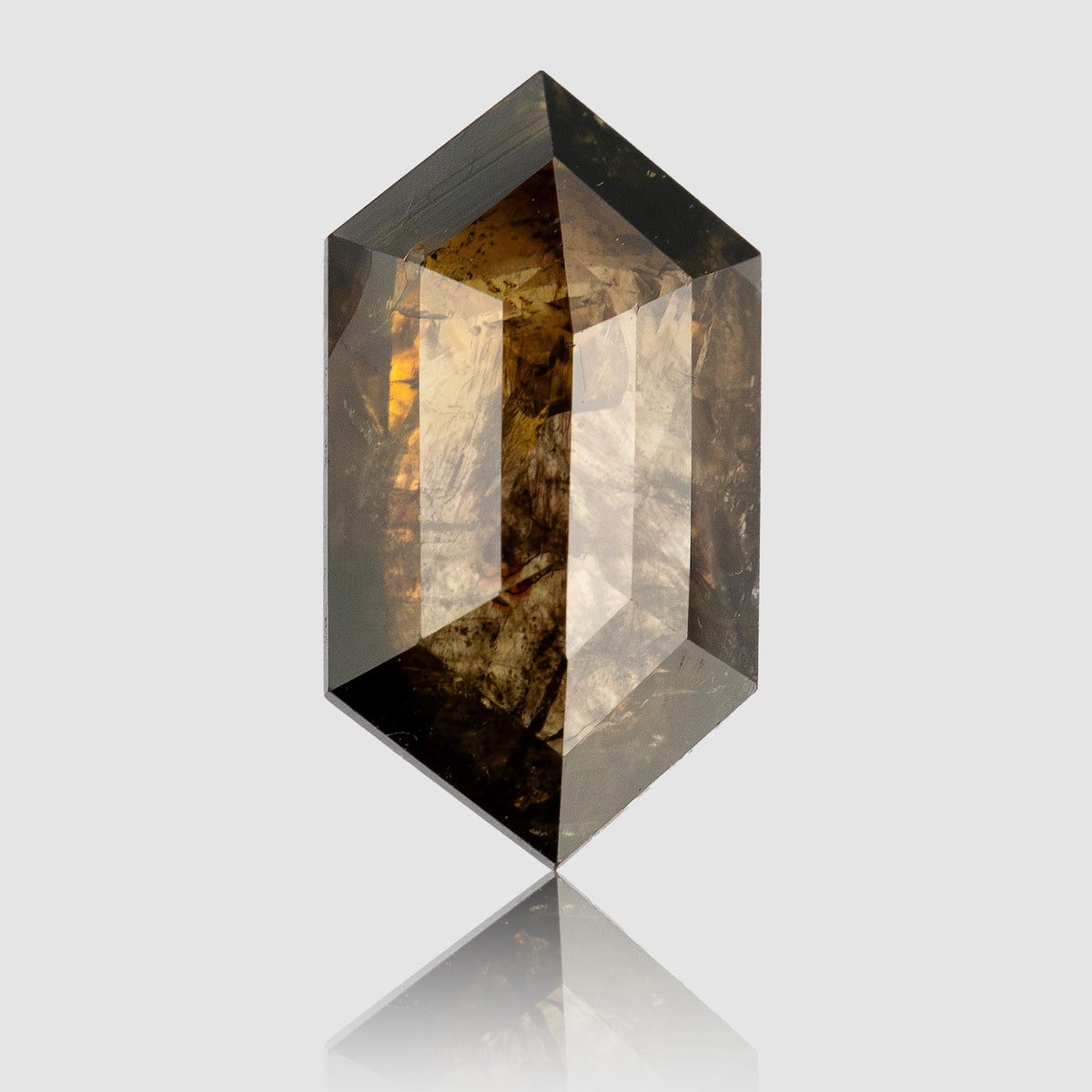 Studio close-up of the brown elongated hexagon diamond standing upright, showing its pointed outline, angular facets and visible inclusions.