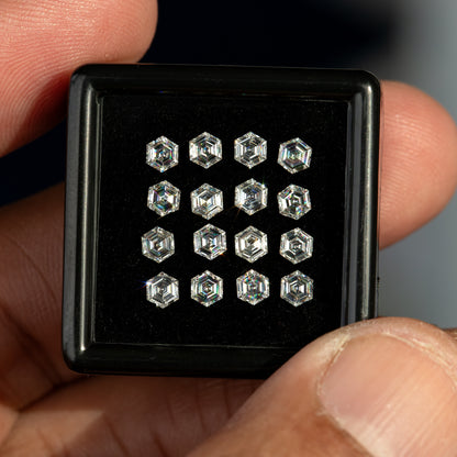 Black tray of face-up hexagonal diamonds held between fingers, showing their outline and matching arrangement.