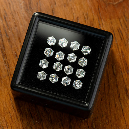 Black tray on a wooden surface containing arranged hexagonal diamonds, viewed from a shallow angle.