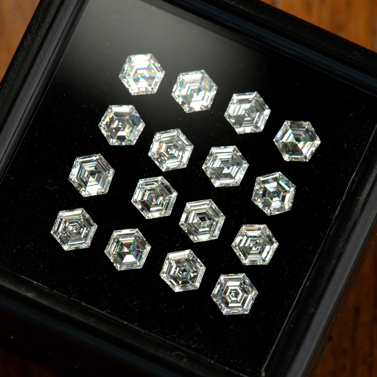 Oblique close-up of diamonds in a black tray, showing bright and dark step-facet reflections.