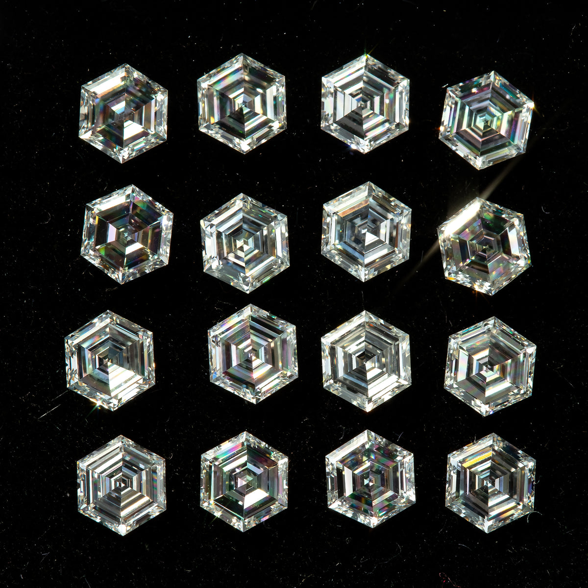 Face-up view of photographed hexagonal step-cut diamonds arranged in a black tray, showing concentric facets and varied reflections.