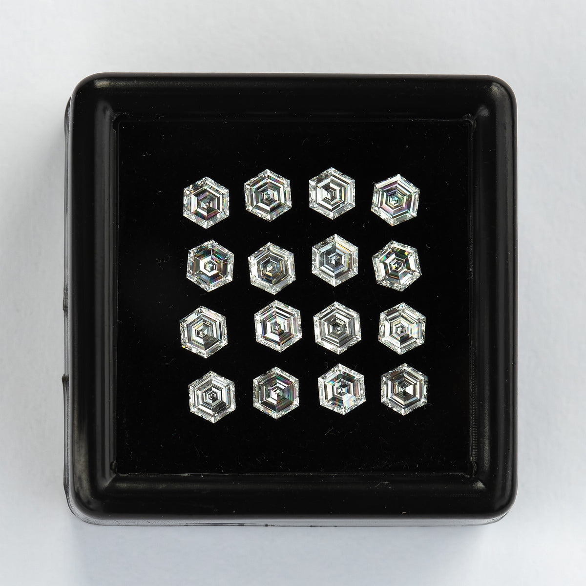 Straight-on black tray of arranged face-up hexagonal diamonds against a pale background.