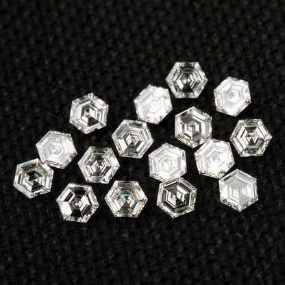Loose hexagonal diamonds on black fabric in mixed orientations, showing both step-facet faces and differently reflecting reverse views.