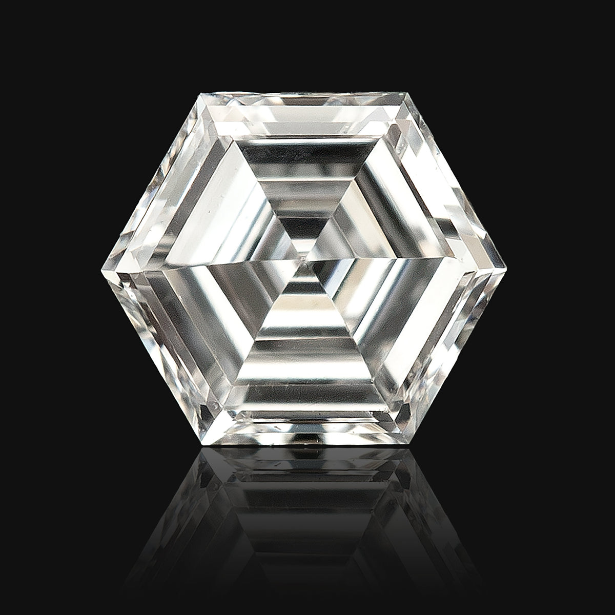 Digitally isolated close-up of a hexagonal step-cut diamond on black, with a decorative reflection beneath it.