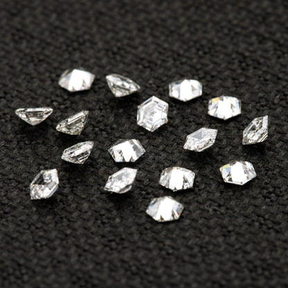 Scattered hexagonal diamonds on black fabric at different inclinations, showing side and reverse-facing views.