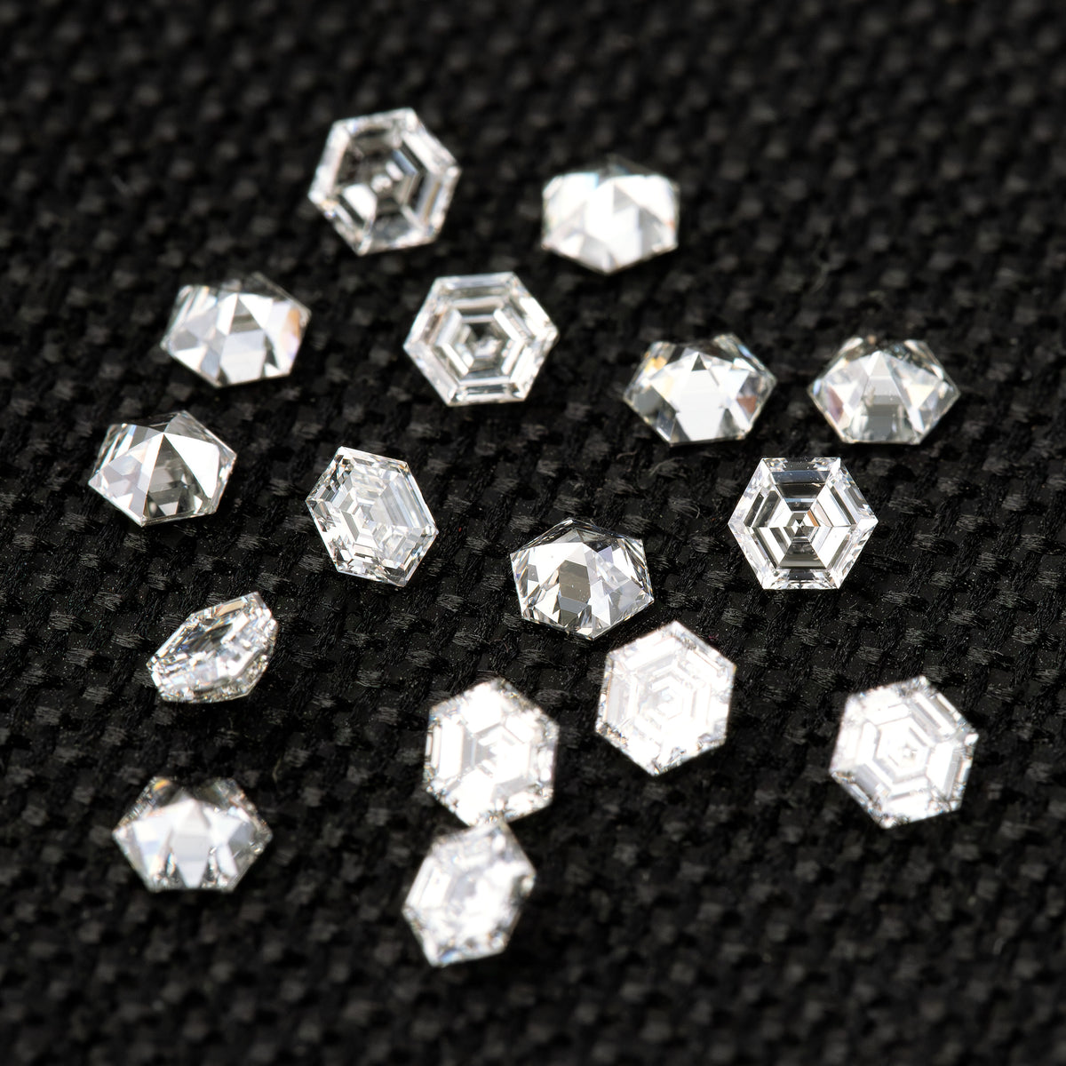 Alternate arrangement of loose hexagonal diamonds on black fabric, with mixed orientations and varied reflections.