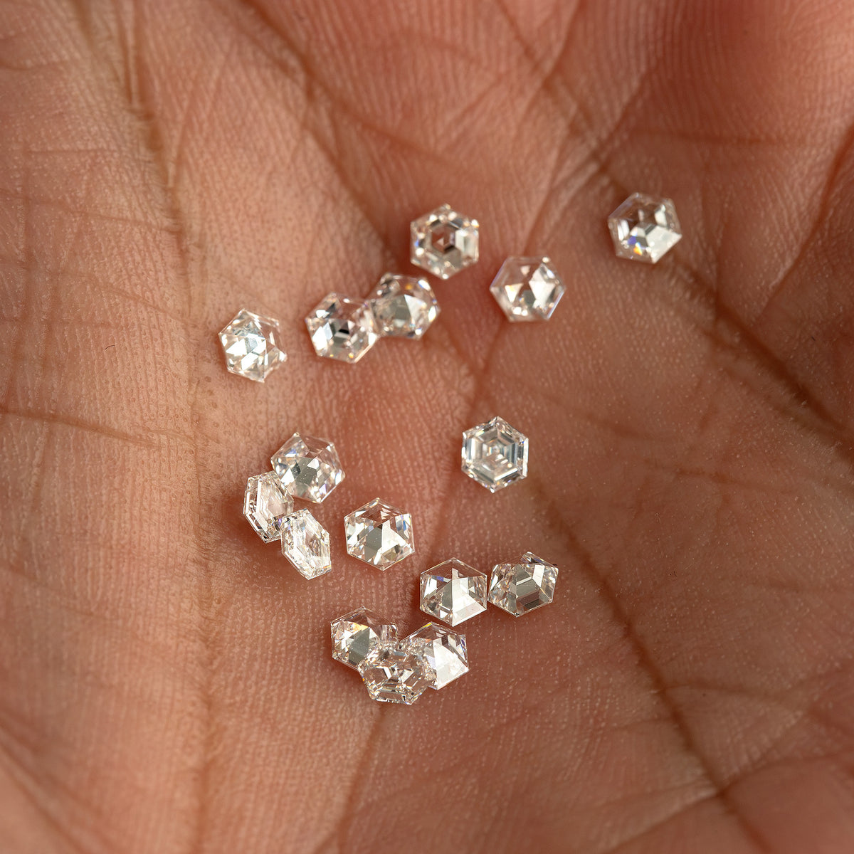 Alternate palm view of small hexagonal diamonds with mixed bright and dark facet reflections.
