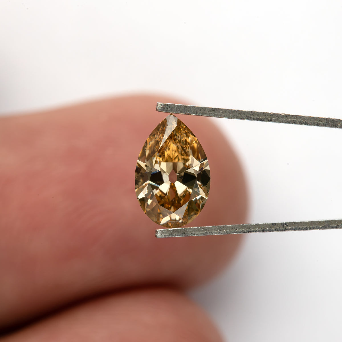 Wider face-up view in tweezers against a fingertip. IGI-PS-5923-0103CT.