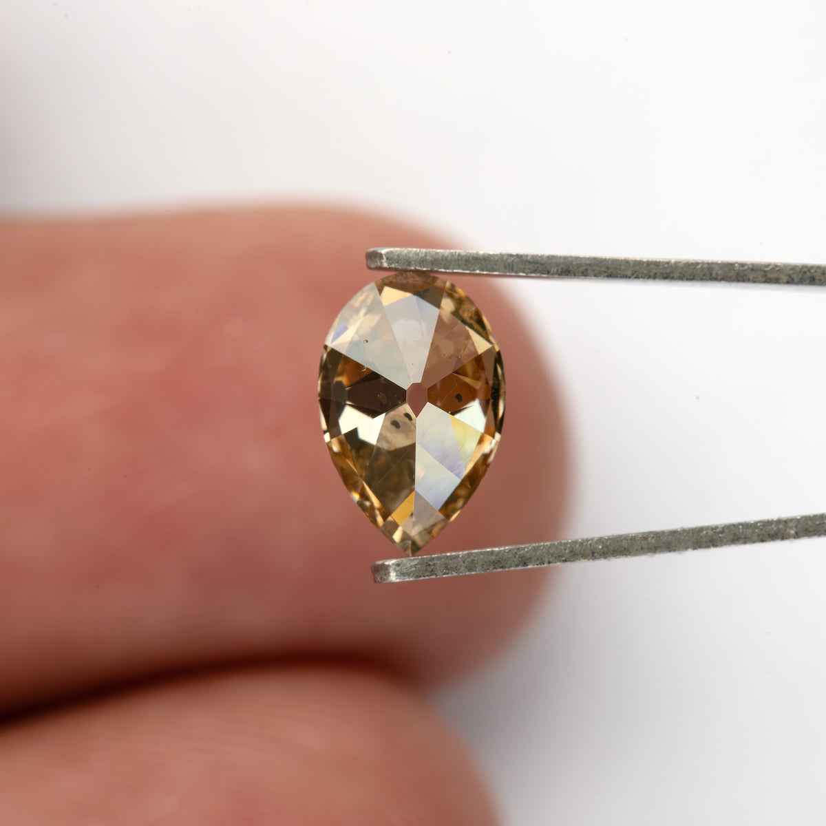 Wider pavilion view in tweezers against a fingertip. IGI-PS-5923-0103CT.
