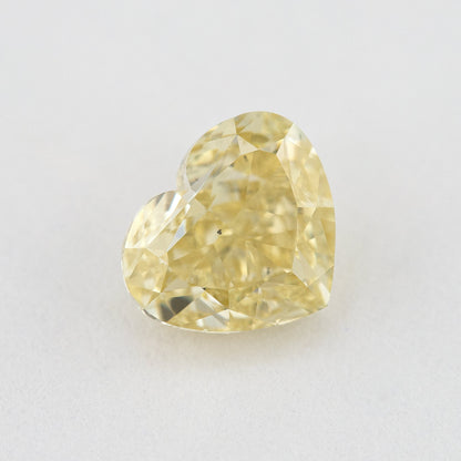 Face-up close-up of the yellow heart diamond on a pale background, showing its complete outline and crown facet reflections.