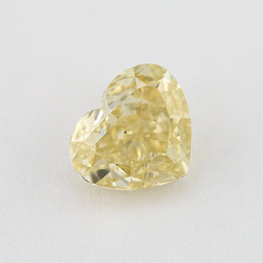 Face-up close-up of the yellow heart diamond on a pale background, showing its complete outline and crown facet reflections.