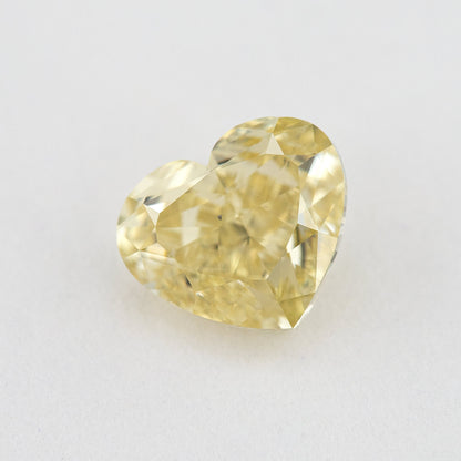 Alternate angled face-up view of the yellow heart diamond on a pale background, with a different pattern of light and dark facet reflections.