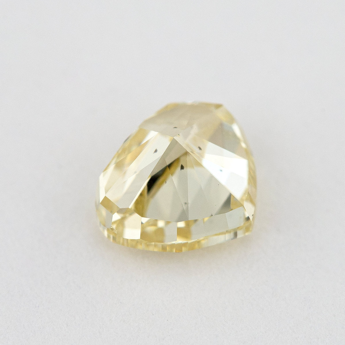 Low tilted view of the yellow heart diamond, showing broad pavilion facets and the depth below its crown.