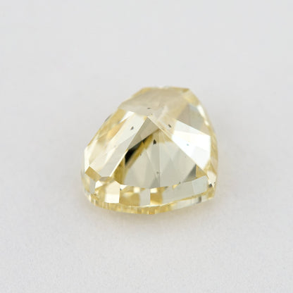 Low tilted view of the yellow heart diamond, showing broad pavilion facets and the depth below its crown.