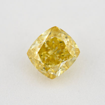 Face-up view of a yellow cushion-shaped natural diamond on a pale surface, showing its complete outline and crown facets.