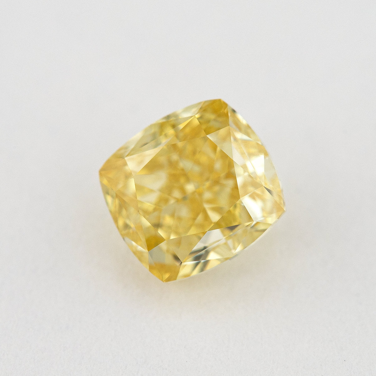Tilted crown view of the yellow cushion-shaped natural diamond, showing a different pattern of bright and dark facet reflections.