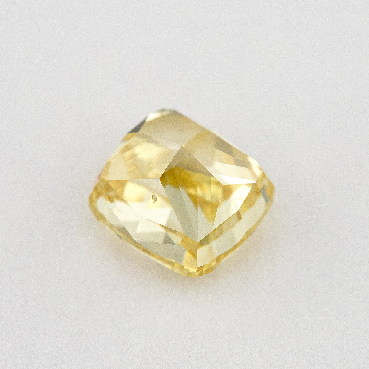 Low side view of the yellow cushion-shaped natural diamond, showing the crown, girdle and pavilion facets.