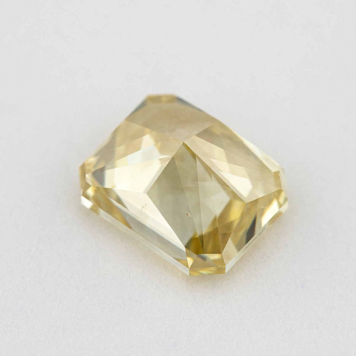 Low tilted view of the yellow radiant diamond, showing broad pavilion facets and the depth below its crown.