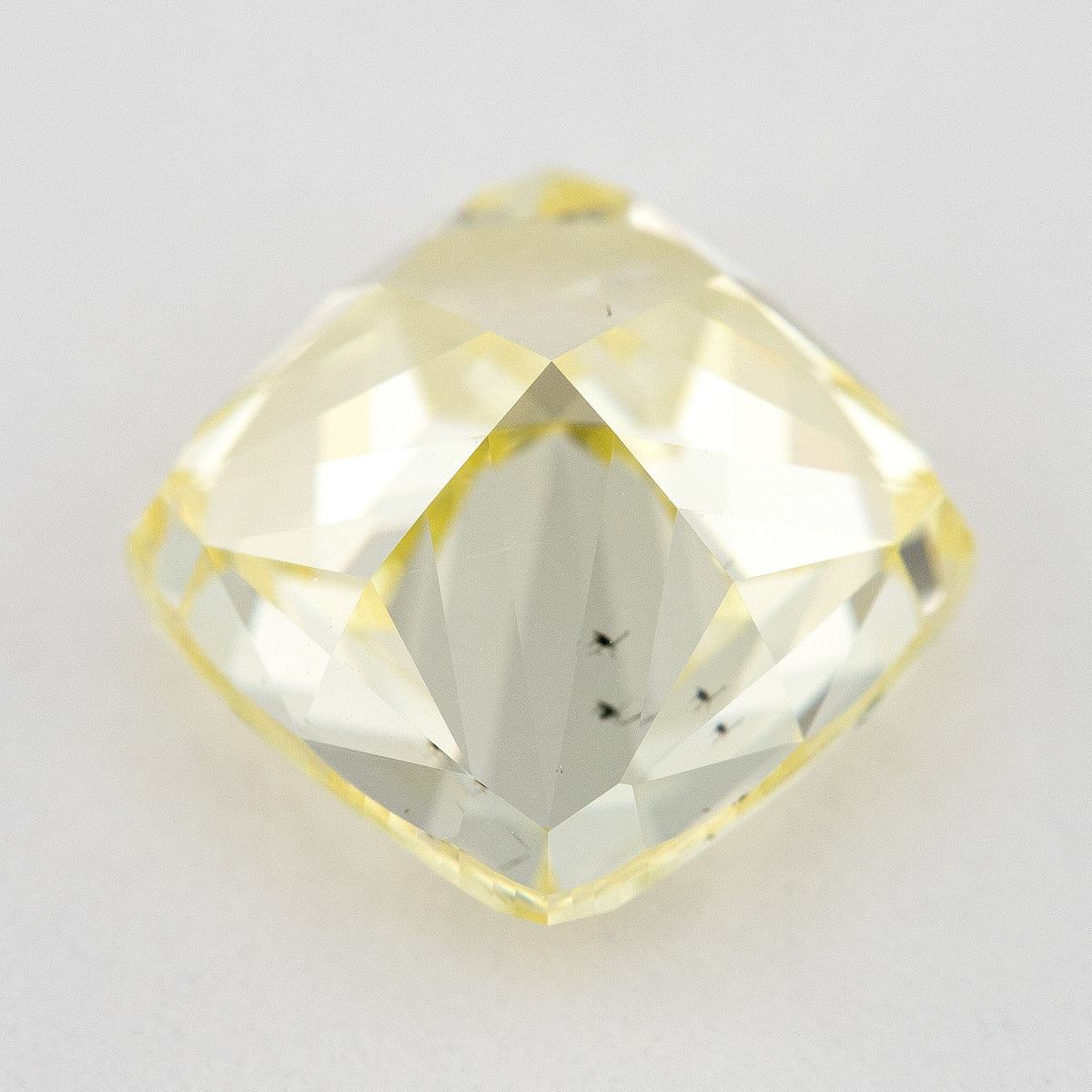 Back view of the yellow cushion-shaped natural diamond, showing broad pavilion facets and dark internal characteristics.