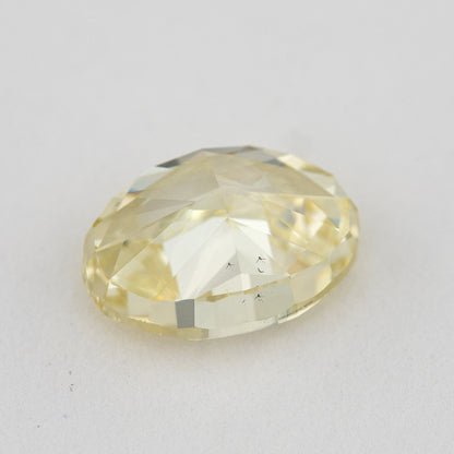 Low tilted view of the yellow oval diamond, showing broad pavilion facets and the depth below its crown.
