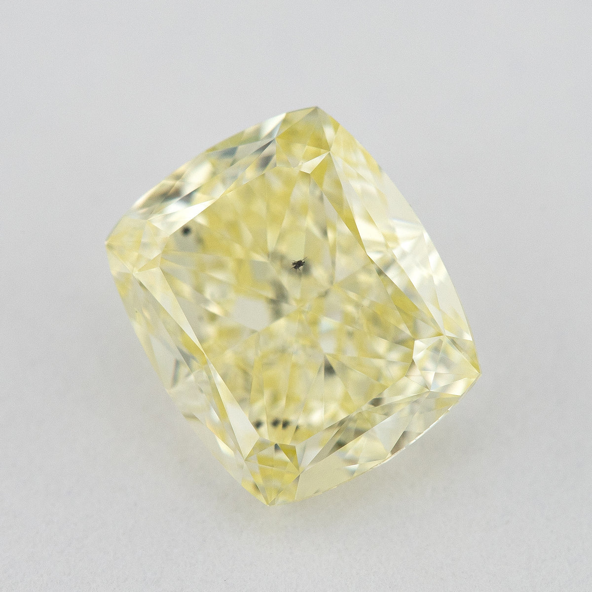 Alternate angled face-up view of the yellow cushion diamond on a pale background, with a different pattern of light and dark facet reflections.