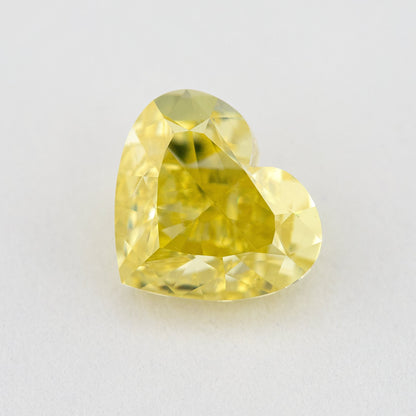 Alternate angled face-up view of the yellow heart diamond on a pale background, with a different pattern of light and dark facet reflections.