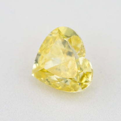 Tilted face-up view of the yellow heart-shaped diamond, showing both lobes, its point and changing facet reflections.