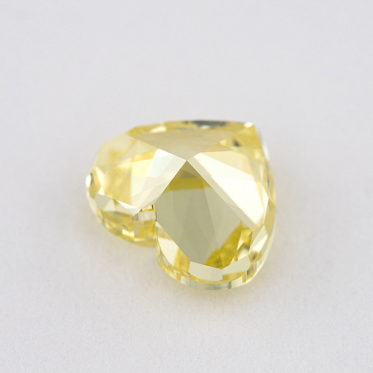 Low tilted view of the yellow heart diamond, showing broad pavilion facets and the depth below its crown.