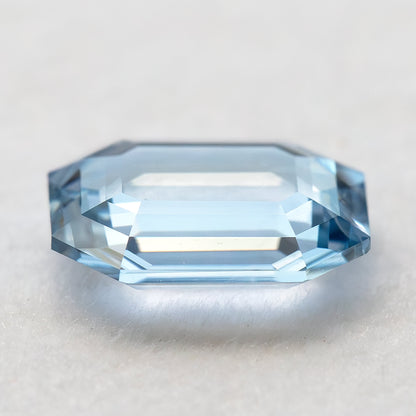 Low-angle edge view of light blue sapphire highlighting shallow proportions and side facets.