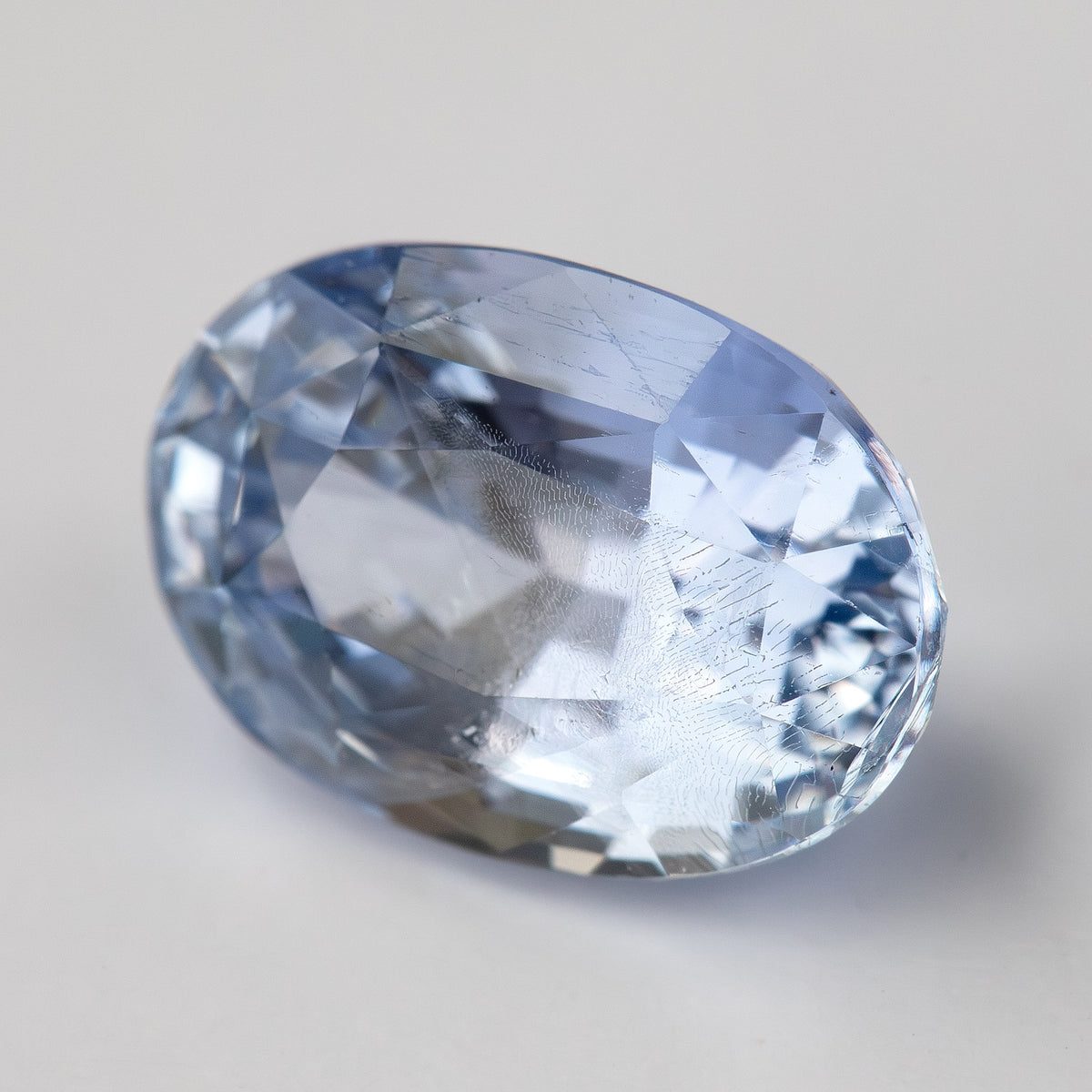 Alternate close face-up view of the oval sapphire, showing soft blue color and changing facet reflections.