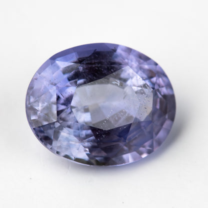 Lavender-blue oval sapphire with visible inclusions tilted face-up, showing changing light reflections. View 11.