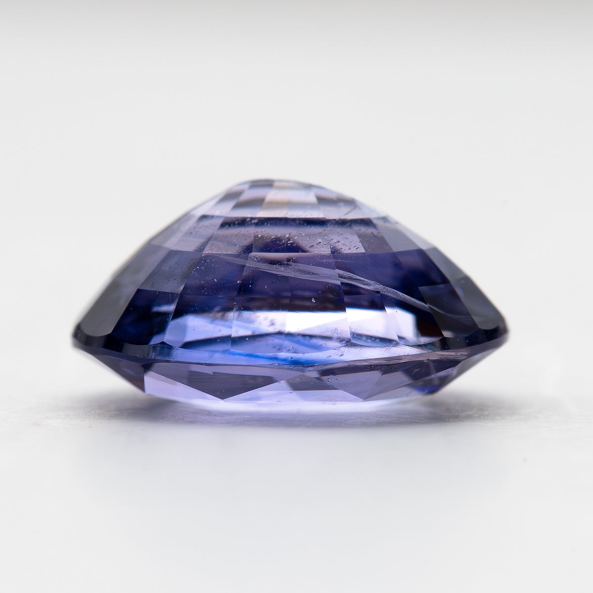 Lavender-blue oval sapphire with visible inclusions viewed from the side, showing crown and pavilion depth. View 14.