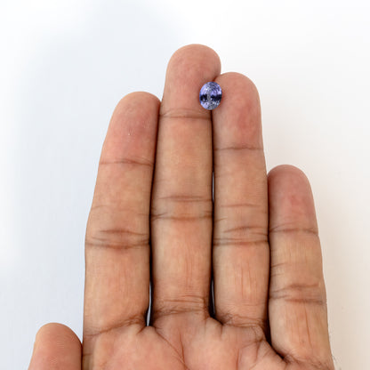Lavender-blue oval sapphire with visible inclusions shown against a hand for scale. View 4.