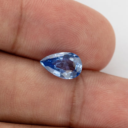 Alternate hand-scale angle of the pear mixed-cut sapphire, with bright icy-blue facets, deeper blue flashes and a purplish central reflection.