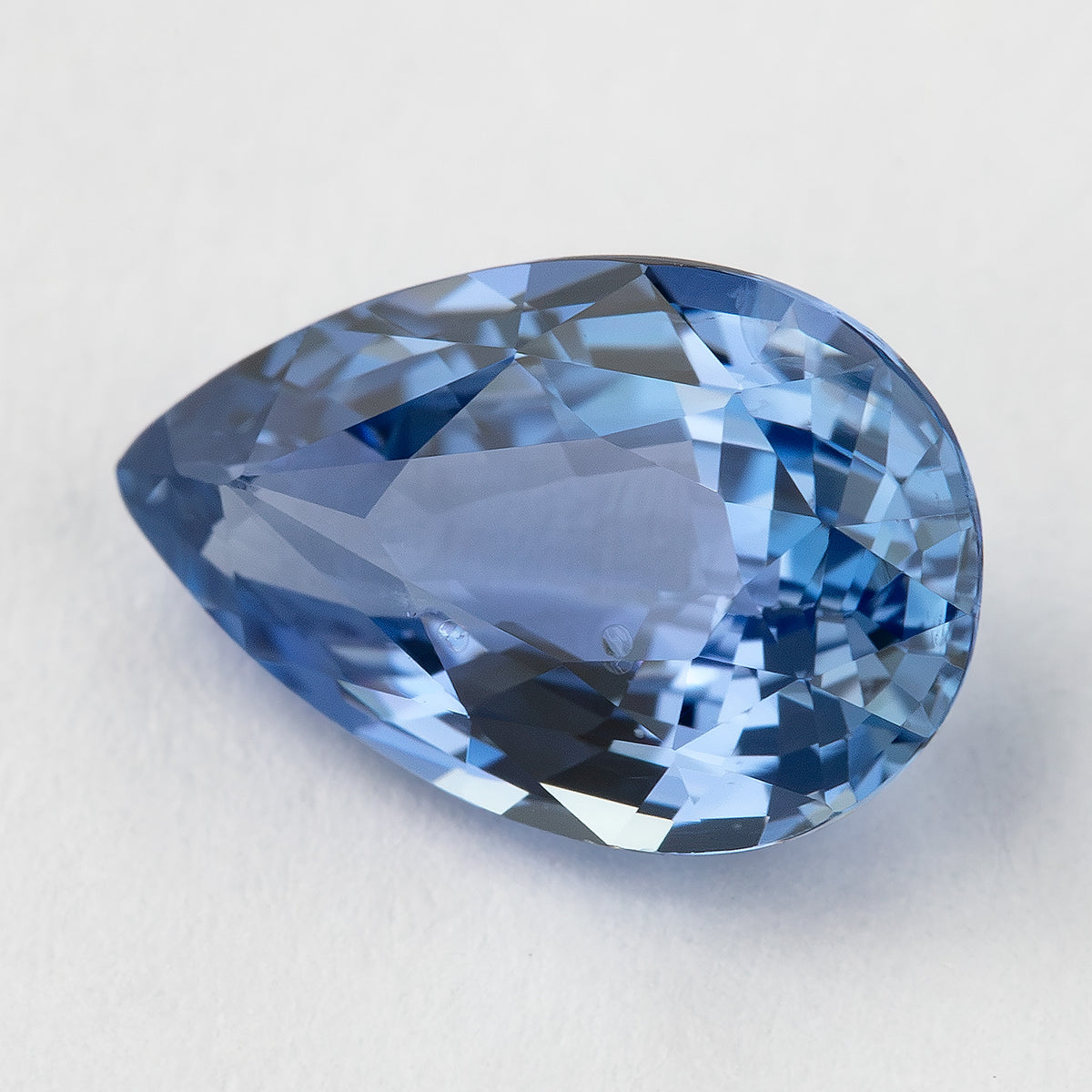 Face-up light blue pear sapphire on white, showing mixed-cut facets and its pointed outline.
