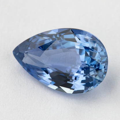 Face-up light blue pear sapphire on white, showing mixed-cut facets and its pointed outline.