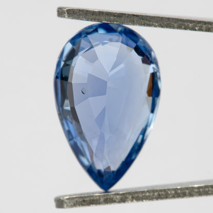Pavilion view of the light blue pear sapphire in tweezers, showing back facets and the pointed tip.