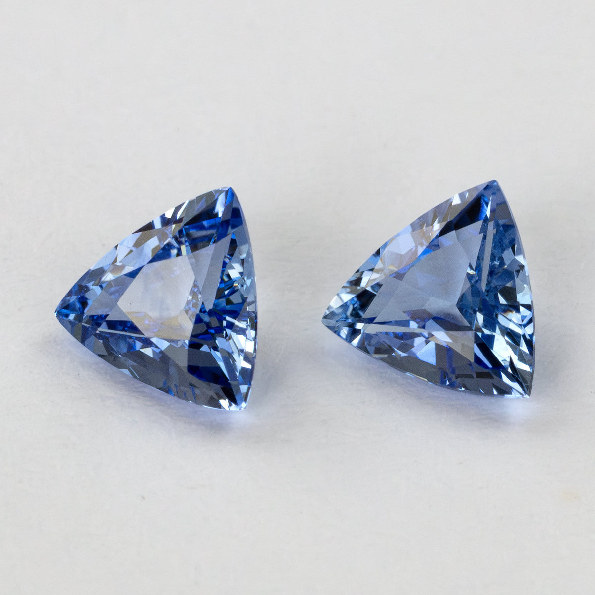 Two blue trillion-cut gemstones shown with slight variations in light reflection.