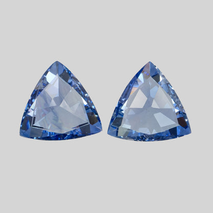 Two blue trillion-cut gemstones against a light grey background.